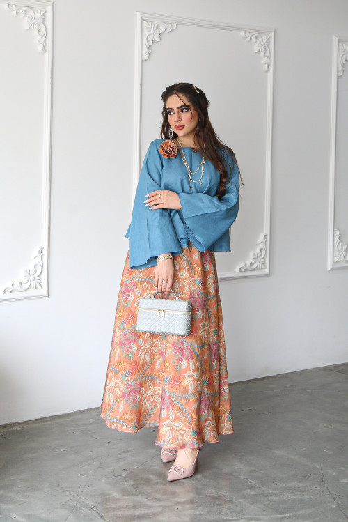 A sky blue linen shirt set with a rose on the shoulder and an apricot printed skirt