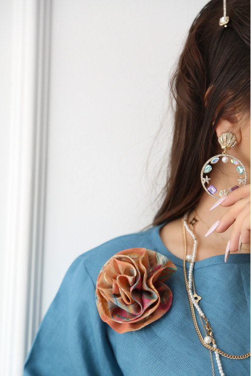 A sky blue linen shirt set with a rose on the shoulder and an apricot printed skirt