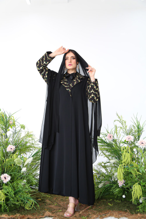 Abaya with black linen at the top, gold and green embroidery, and soft pleats at the back.