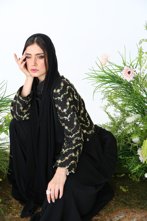 Abaya with black linen at the top, gold and green embroidery, and soft pleats at the back.